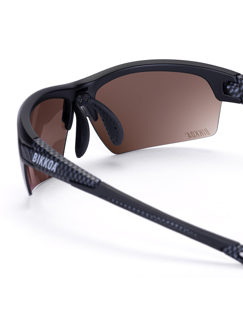 Gafas deportivas BIKKOA GOAT color dorada, detalle de la patilla flexible TR90 y la lente dorada REVO en configuración doble - Dorada