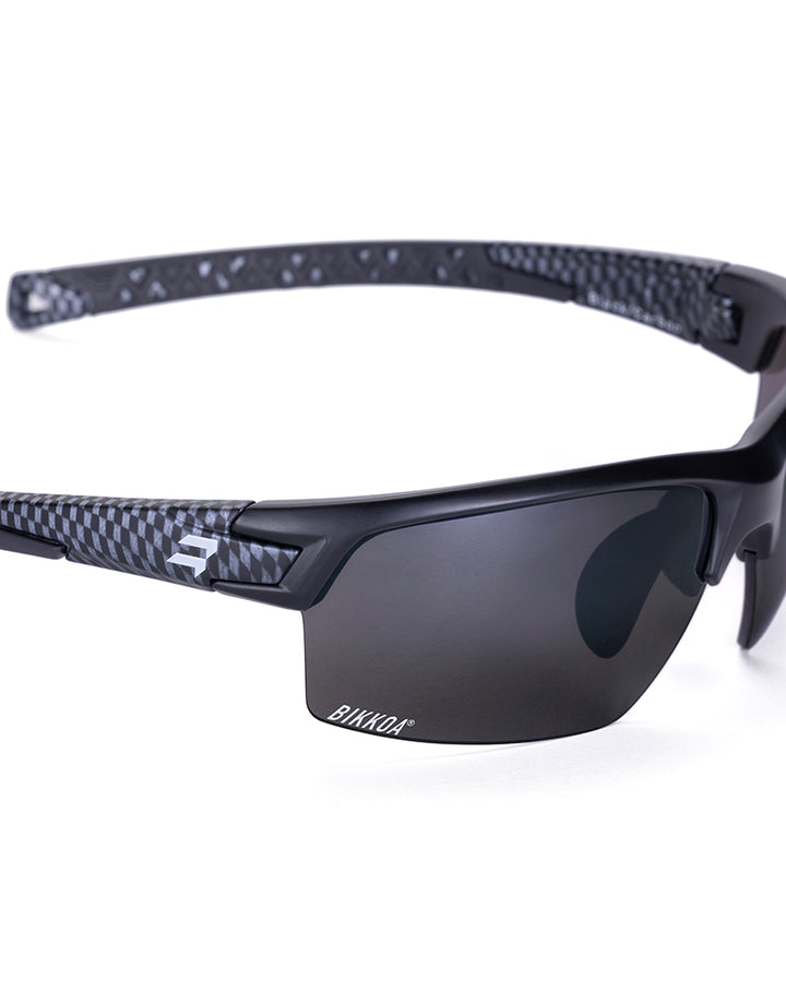 Gafas deportivas BIKKOA GOAT color negra, detalle de la patilla flexible TR90 y la lente negra en configuración doble - Negra