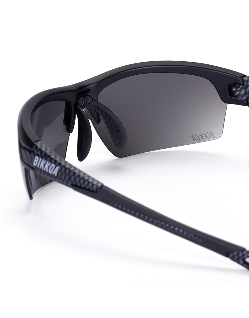 Gafas deportivas BIKKOA GOAT color negra, detalle de la patilla flexible TR90 y la lente negra en configuración doble - Negra