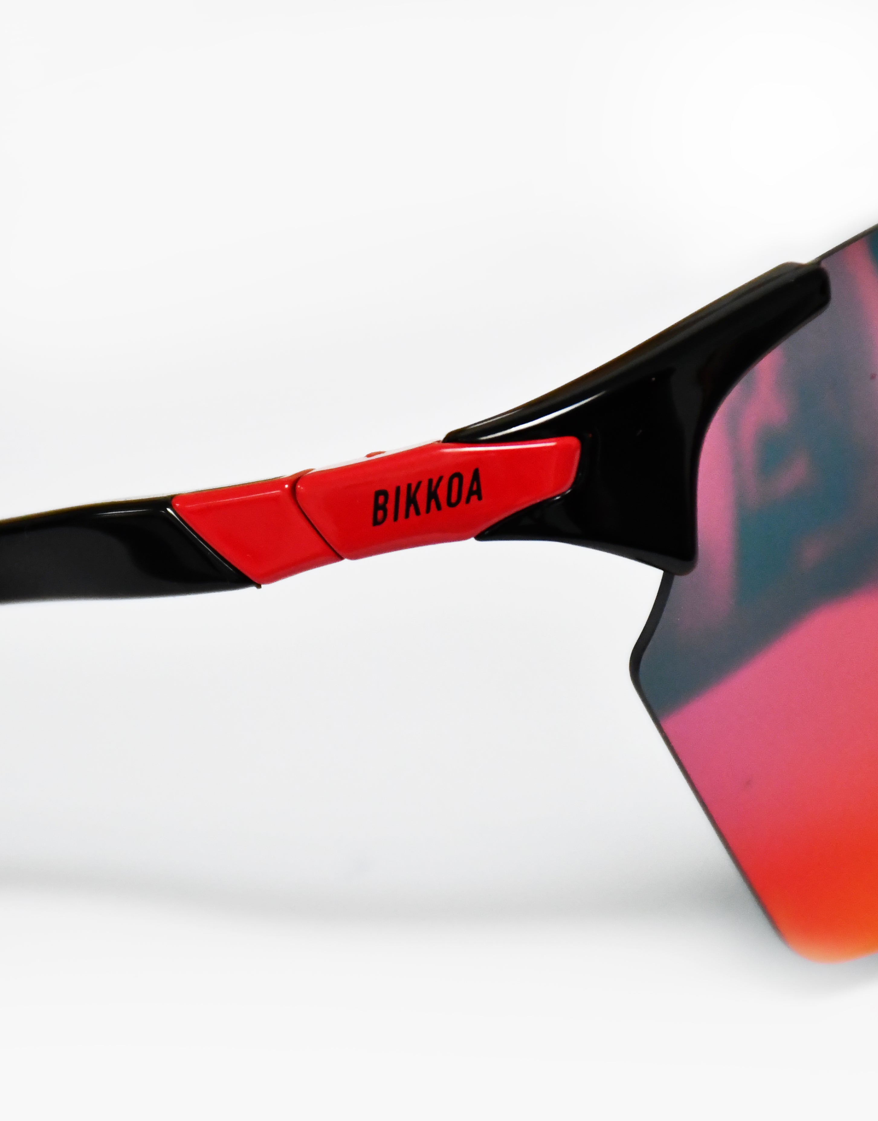 Gafas deportivas polarizadas BIKKOA VYROX con lente roja polarizada y montura negra envolvente, detalle técnico del acabado polarizado y soporte lateral del modelo VYROX - Roja